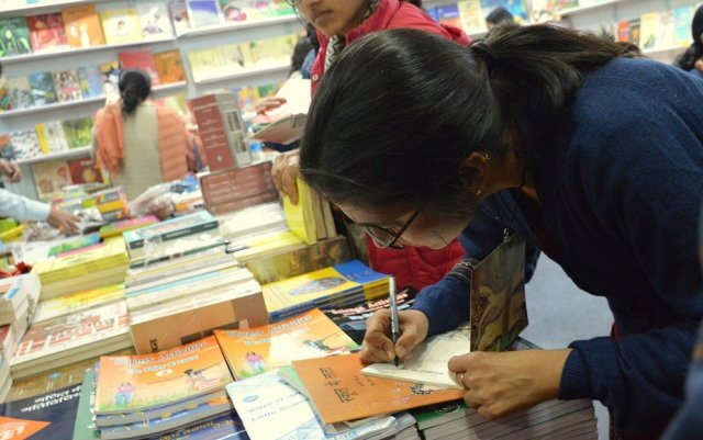 लेखिका रिन्चिन अपनी किताब की प्रतियों पर हस्ताक्षर करते हुए 